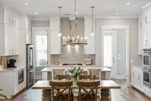 kitchen featuring hanging light fixtures, white cabinets, and stainless steel appliances