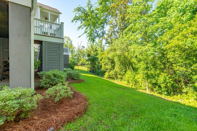 view of yard with a balcony and ceiling fan