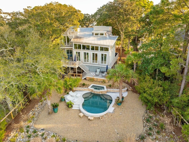 rear view of property with a swimming pool with hot tub, a sunroom, a patio, and a balcony