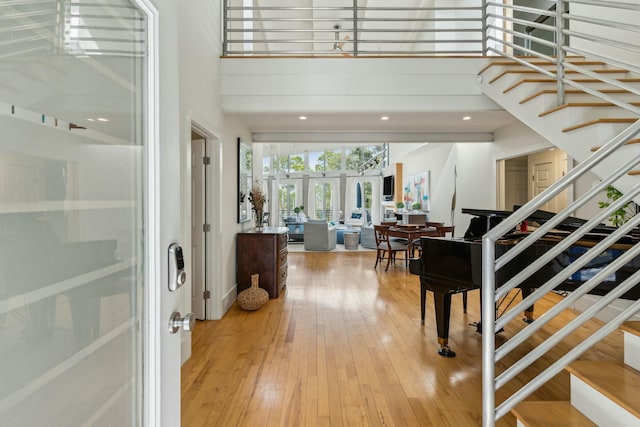 foyer entrance with hardwood / wood-style floors, a towering ceiling, and french doors