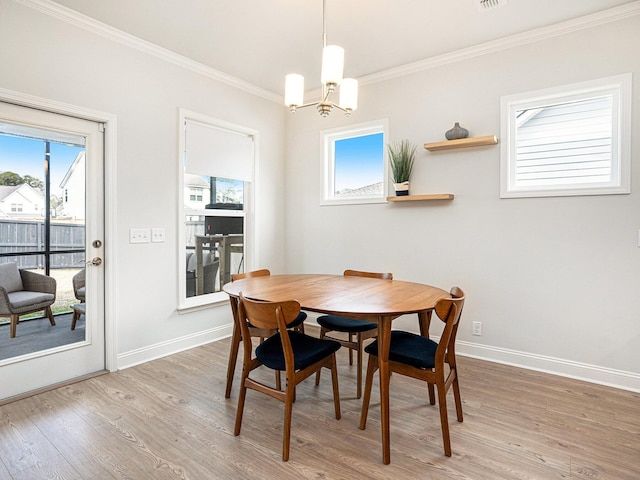 dining area featuring light wood-style floors, ornamental molding, baseboards, and an inviting chandelier