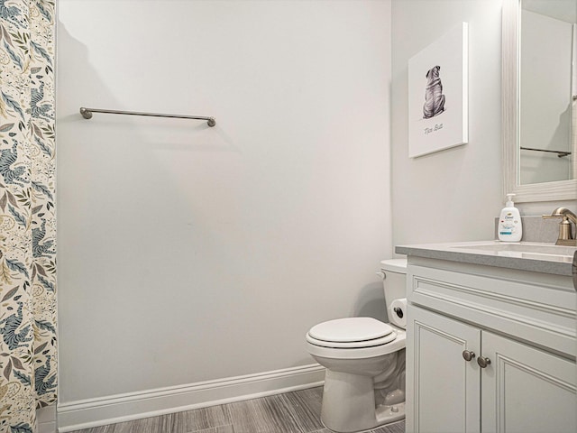 full bathroom with wood finished floors, vanity, toilet, and baseboards