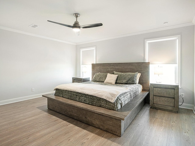 bedroom with ornamental molding, light wood-style flooring, visible vents, and baseboards