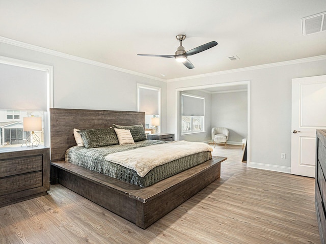 bedroom with ceiling fan, light wood-style flooring, visible vents, baseboards, and crown molding