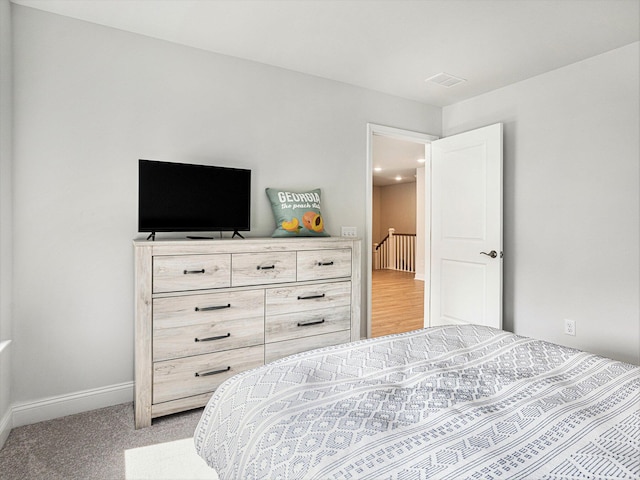 bedroom featuring visible vents, light carpet, and baseboards