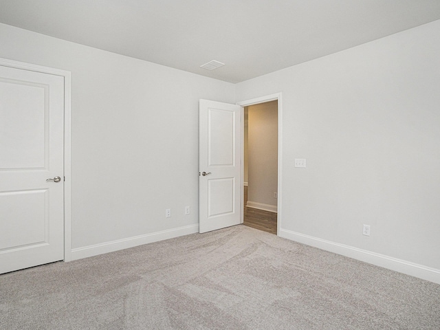 empty room with light carpet, visible vents, and baseboards