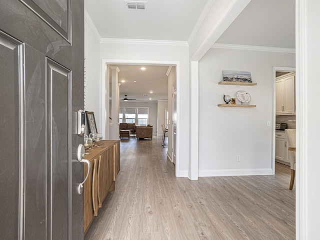 foyer featuring visible vents, crown molding, baseboards, and wood finished floors