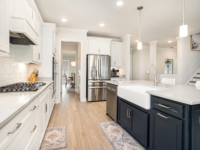 kitchen with pendant lighting, light countertops, appliances with stainless steel finishes, white cabinetry, and a sink