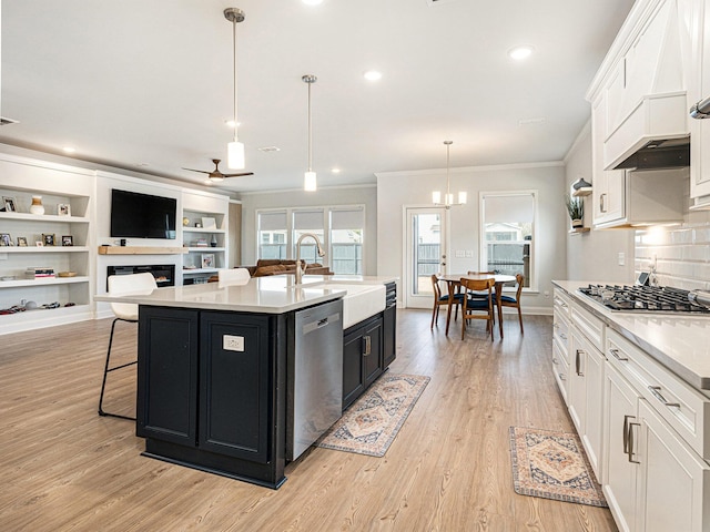 kitchen with an island with sink, appliances with stainless steel finishes, light countertops, and decorative light fixtures