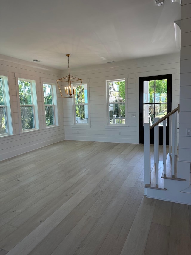 interior space featuring a notable chandelier, wooden walls, and wood-type flooring