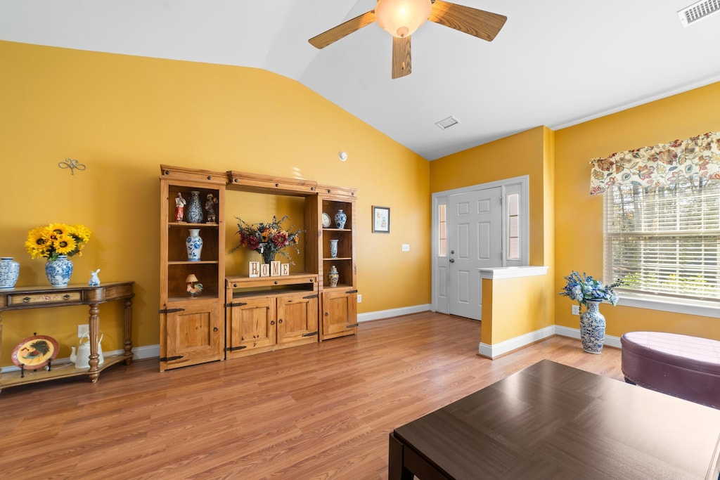 living room with lofted ceiling, hardwood / wood-style floors, and ceiling fan