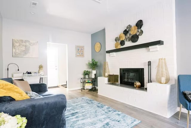 living room with wood finished floors and a brick fireplace