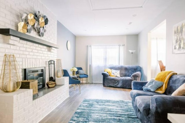 living room with wood finished floors and a brick fireplace