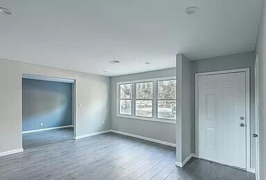 empty room with baseboards and dark wood-type flooring