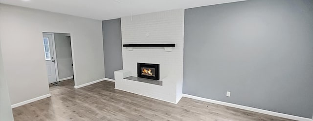 unfurnished living room featuring baseboards, a fireplace, and wood finished floors