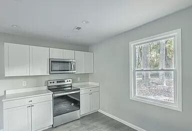 kitchen with stainless steel appliances, white cabinets, baseboards, and light countertops