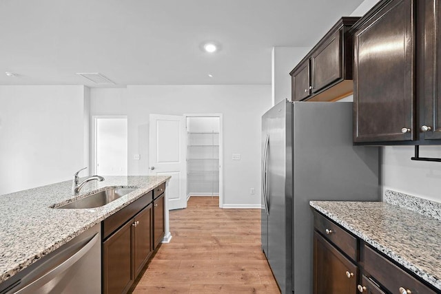261 Celestial Blvd, Summerville, SC 29486 - kitchen with stainless steel appliances, a sink, light wood finished floors, dark brown cabinets, and light stone counters