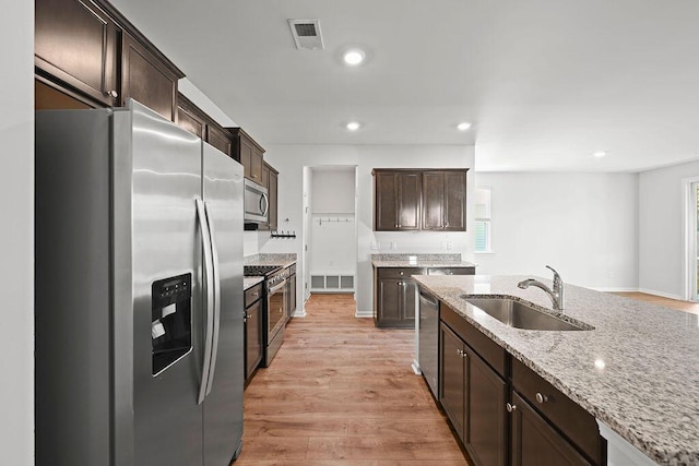 261 Celestial Blvd, Summerville, SC 29486 - kitchen featuring appliances with stainless steel finishes, a sink, dark brown cabinetry, light stone countertops, and light wood-style flooring