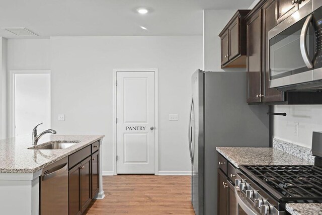 261 Celestial Blvd, Summerville, SC 29486 - kitchen featuring appliances with stainless steel finishes, dark brown cabinetry, a sink, light wood-style floors, and light stone countertops