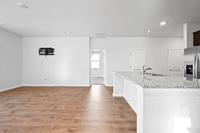 261 Celestial Blvd, Summerville, SC 29486 - kitchen featuring a sink, stainless steel fridge, light wood-type flooring, light stone counters, and baseboards