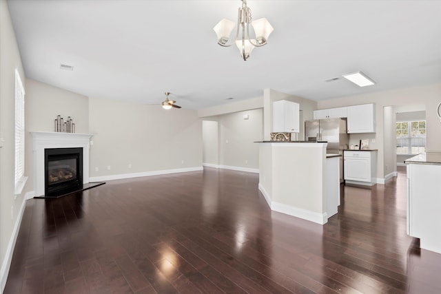 kitchen with dark wood-type flooring, a glass covered fireplace, white cabinets, and stainless steel fridge with ice dispenser