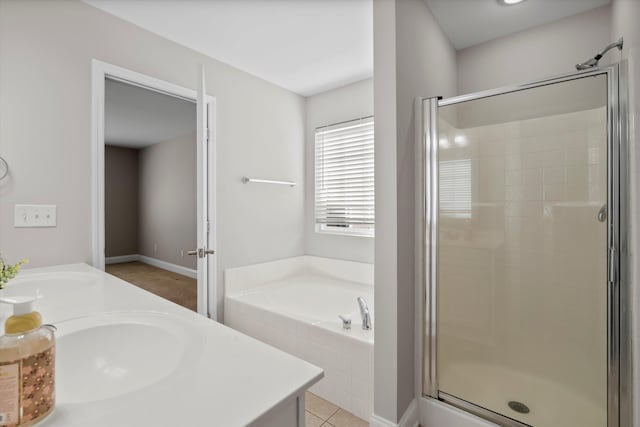 bathroom with a garden tub, double vanity, a stall shower, and a sink