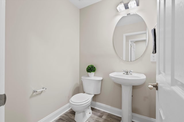 bathroom with toilet, a sink, baseboards, and wood finished floors