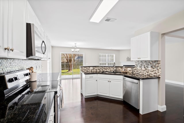 kitchen featuring stainless steel appliances, visible vents, white cabinets, a sink, and a peninsula