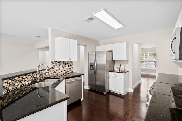 kitchen with dark wood-type flooring, a sink, visible vents, appliances with stainless steel finishes, and dark stone countertops