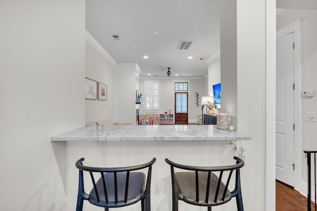 kitchen with ornamental molding, dark wood-type flooring, light stone countertops, and kitchen peninsula