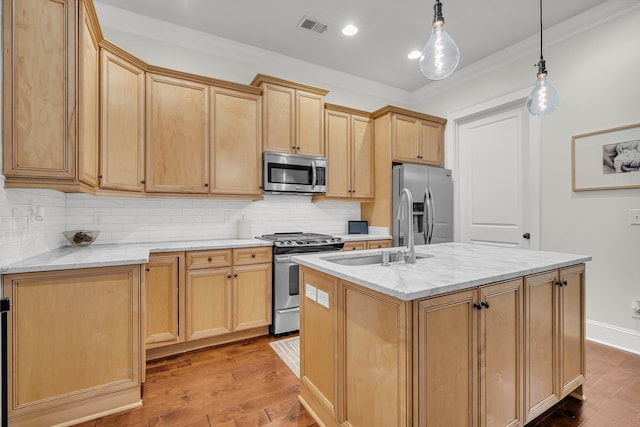 kitchen with an island with sink, appliances with stainless steel finishes, sink, and decorative light fixtures