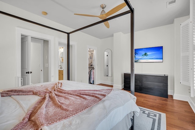 bedroom with ceiling fan, a closet, a walk in closet, and light hardwood / wood-style floors