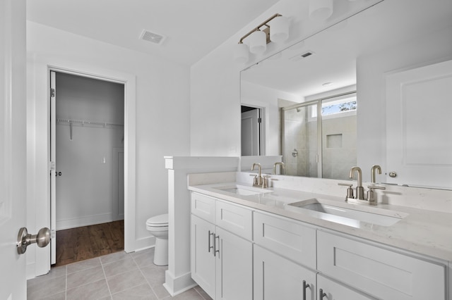 bathroom featuring tile patterned flooring, vanity, toilet, and walk in shower