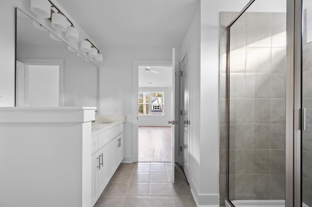 bathroom featuring tile patterned floors, ceiling fan, a shower with door, and vanity