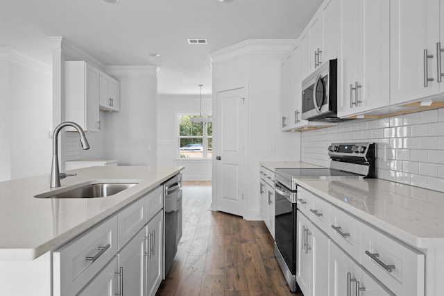 kitchen featuring dark hardwood / wood-style flooring, ornamental molding, stainless steel appliances, sink, and white cabinetry