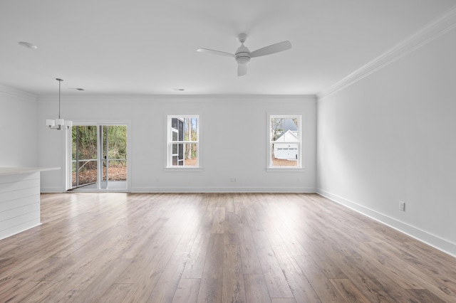 empty room with ceiling fan with notable chandelier, light wood-type flooring, and ornamental molding