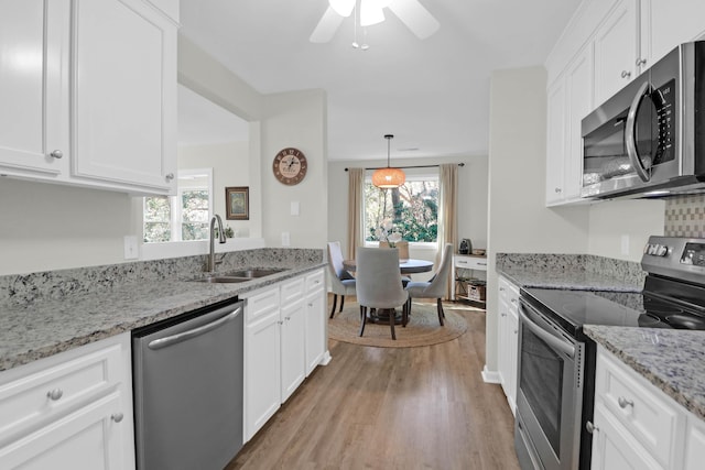 kitchen with a sink, appliances with stainless steel finishes, a wealth of natural light, and white cabinetry