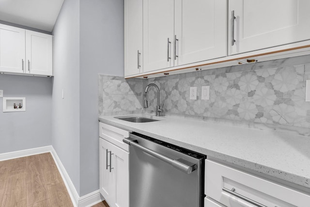 kitchen with light wood-type flooring, light stone counters, stainless steel dishwasher, sink, and white cabinetry