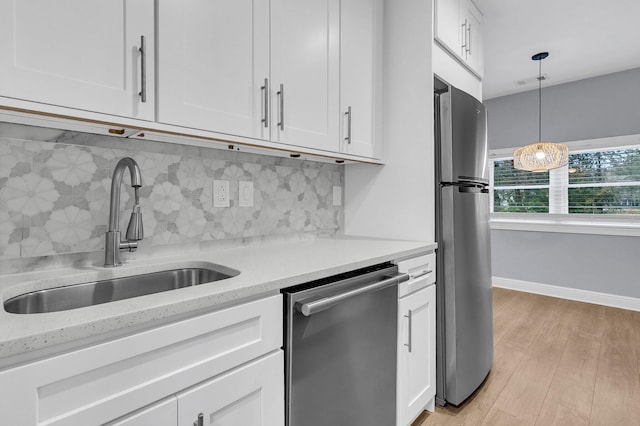 kitchen featuring hanging light fixtures, sink, light wood-type flooring, appliances with stainless steel finishes, and white cabinetry