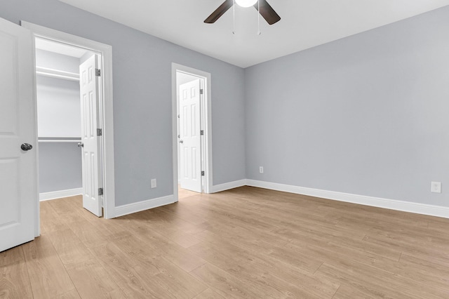 unfurnished bedroom with ceiling fan, light hardwood / wood-style floors, a walk in closet, and a closet