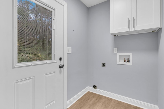 clothes washing area with washer hookup, electric dryer hookup, light hardwood / wood-style floors, and cabinets