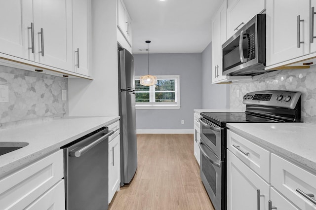 kitchen featuring white cabinetry, stainless steel appliances, light stone counters, and light wood-type flooring