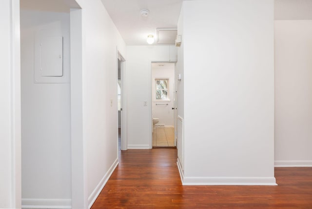 hallway featuring dark wood-style floors, electric panel, and baseboards