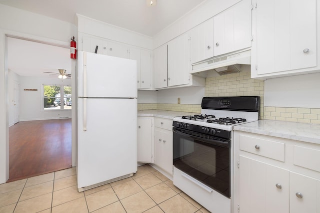 kitchen with gas range, light countertops, freestanding refrigerator, and under cabinet range hood