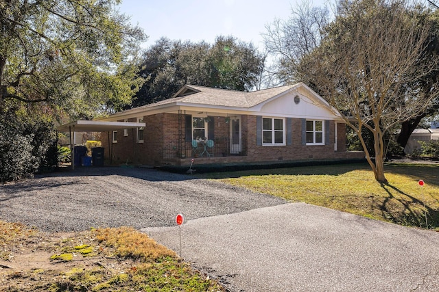 ranch-style home featuring an attached carport, gravel driveway, crawl space, a front lawn, and brick siding