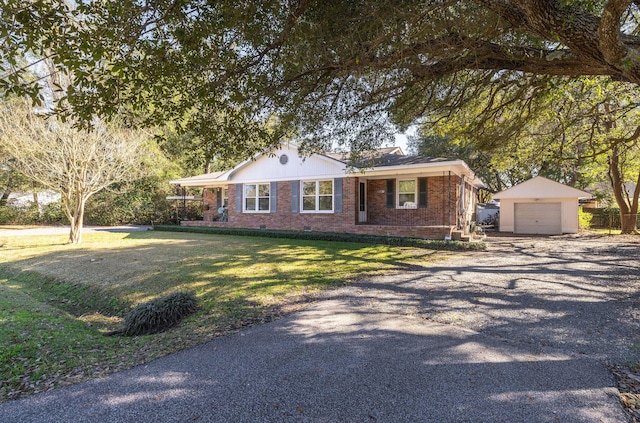 ranch-style home featuring gravel driveway, brick siding, a detached garage, a front yard, and an outdoor structure