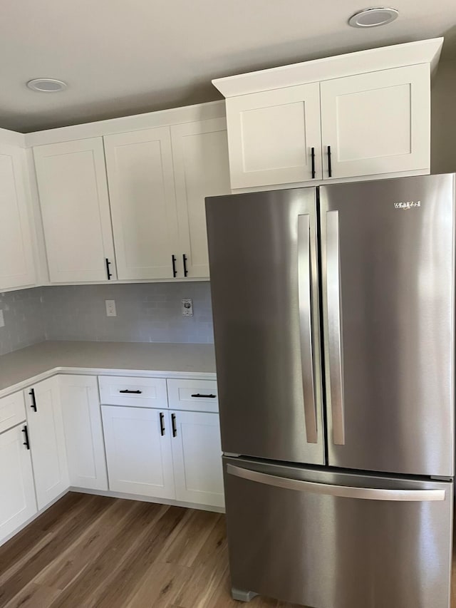 kitchen with backsplash, white cabinetry, dark wood-type flooring, and stainless steel refrigerator