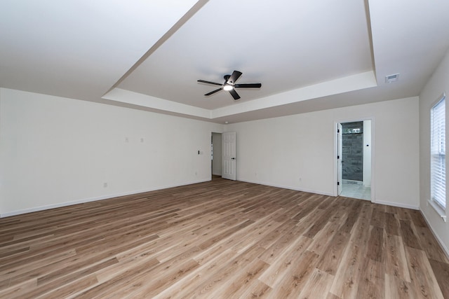 unfurnished room with a raised ceiling and light wood-type flooring