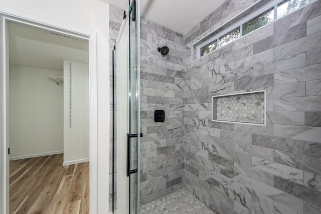 bathroom with wood-type flooring and a tile shower