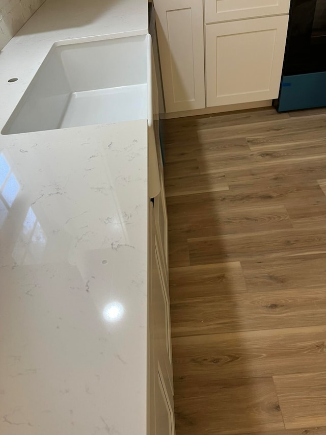 details with white cabinetry, black range oven, and light wood-type flooring